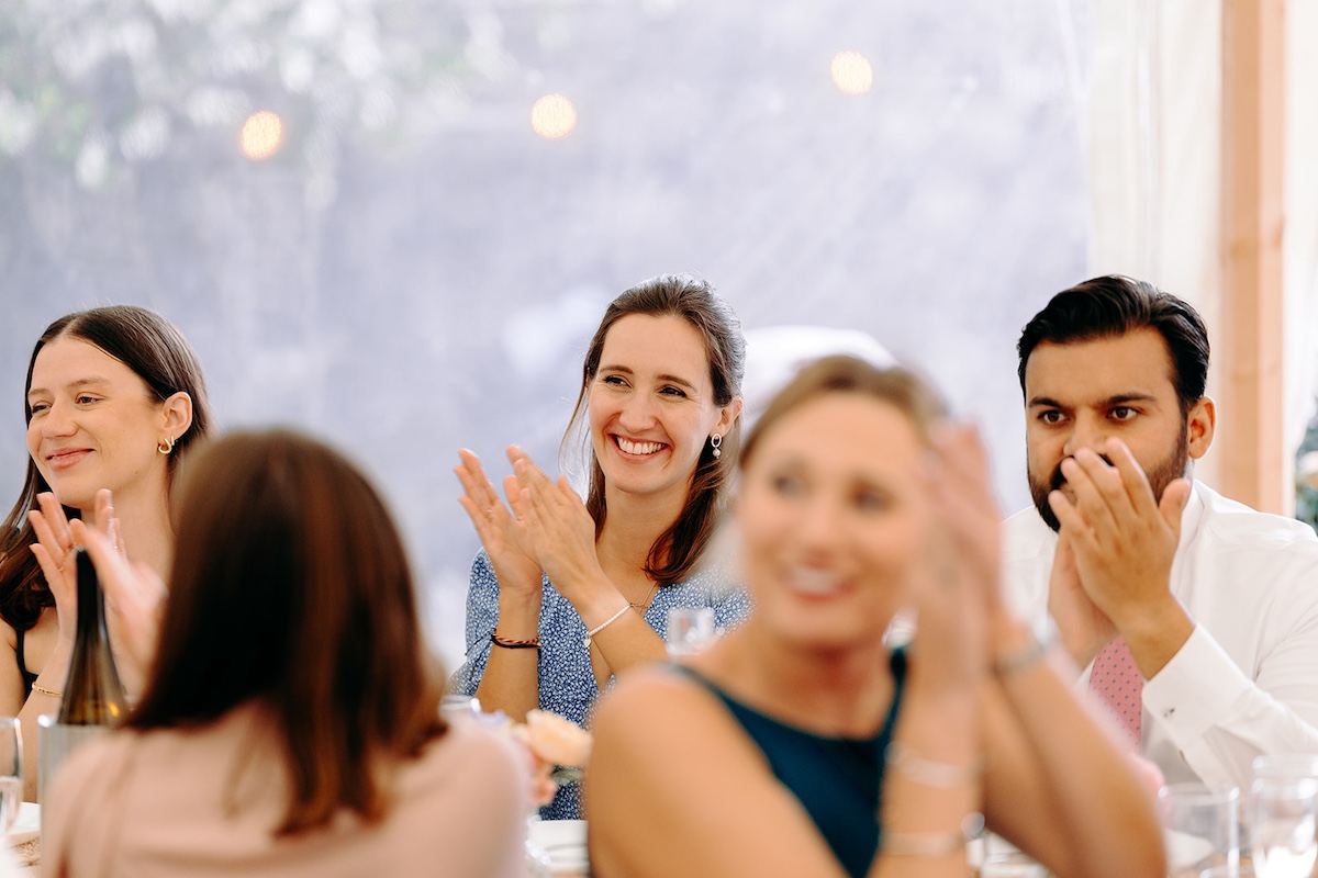 Guests raising glasses and toasting during marquee wedding speeches at Eyam Hall.
