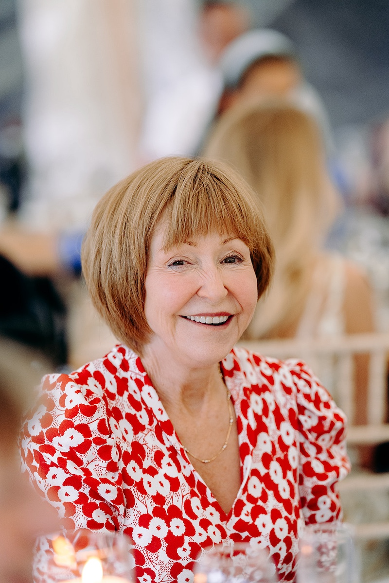 Close-up of smiling guest enjoying wedding speeches at Eyam Hall marquee reception.