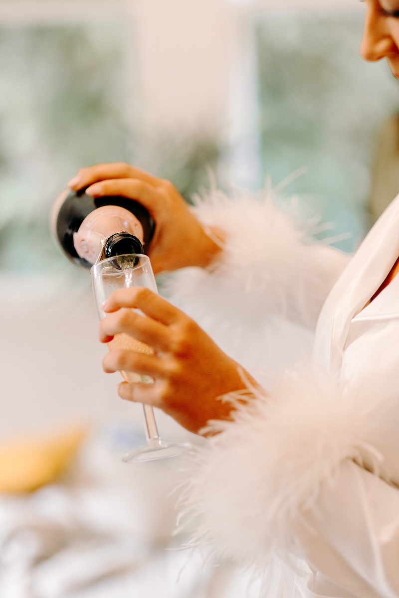 Close-up of bride holding champagne flute while getting ready at Eyam Hall wedding morning.