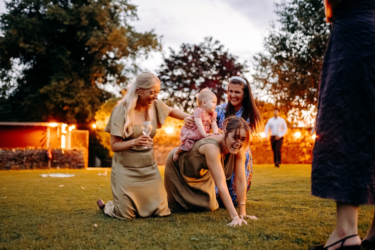 Guests playing with little girl during evening wedding reception at Eyam Hall.