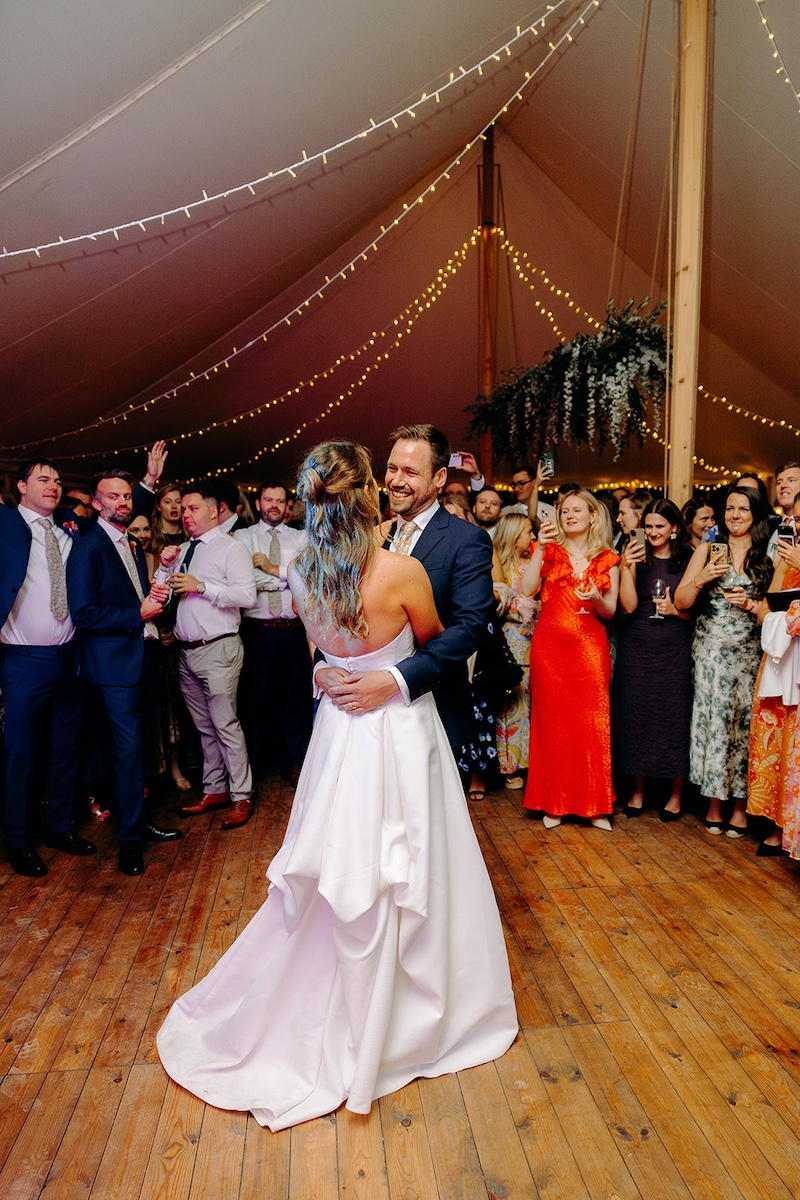 Couple sharing first dance under canopy of fairy lights and hanging foliage at Eyam Hall marquee wedding.
