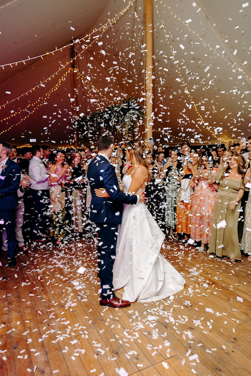 Bride and groom spinning on dance floor under warm amber lights at Eyam Hall wedding.