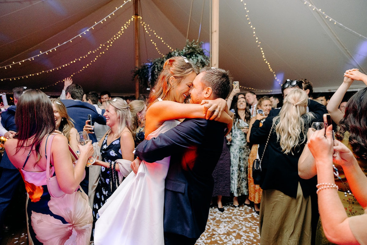 Bride and groom spinning on dance floor under warm amber lights at Eyam Hall wedding.