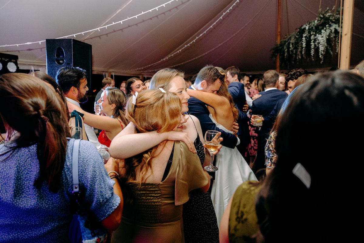 Guests jumping and singing along on crowded dance floor at Eyam Hall wedding party.