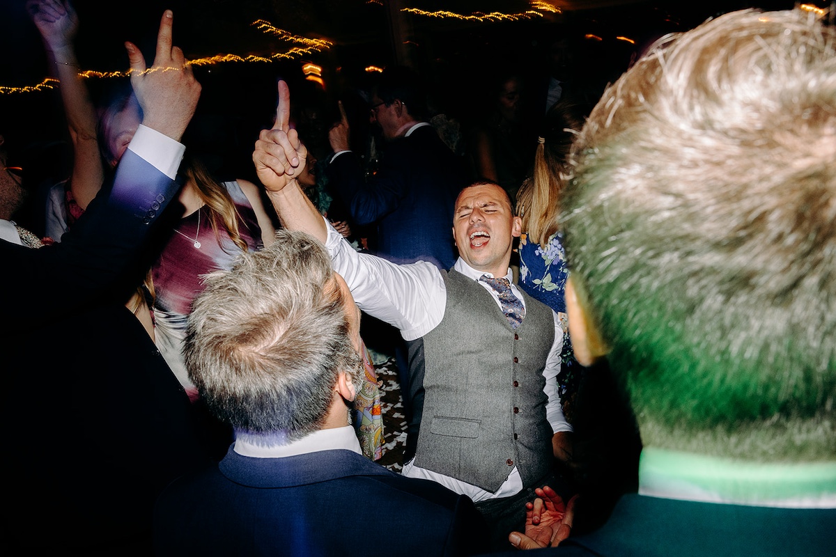 Guests waving hands in the air during energetic party dancing – Derbyshire wedding photographer evening coverage.