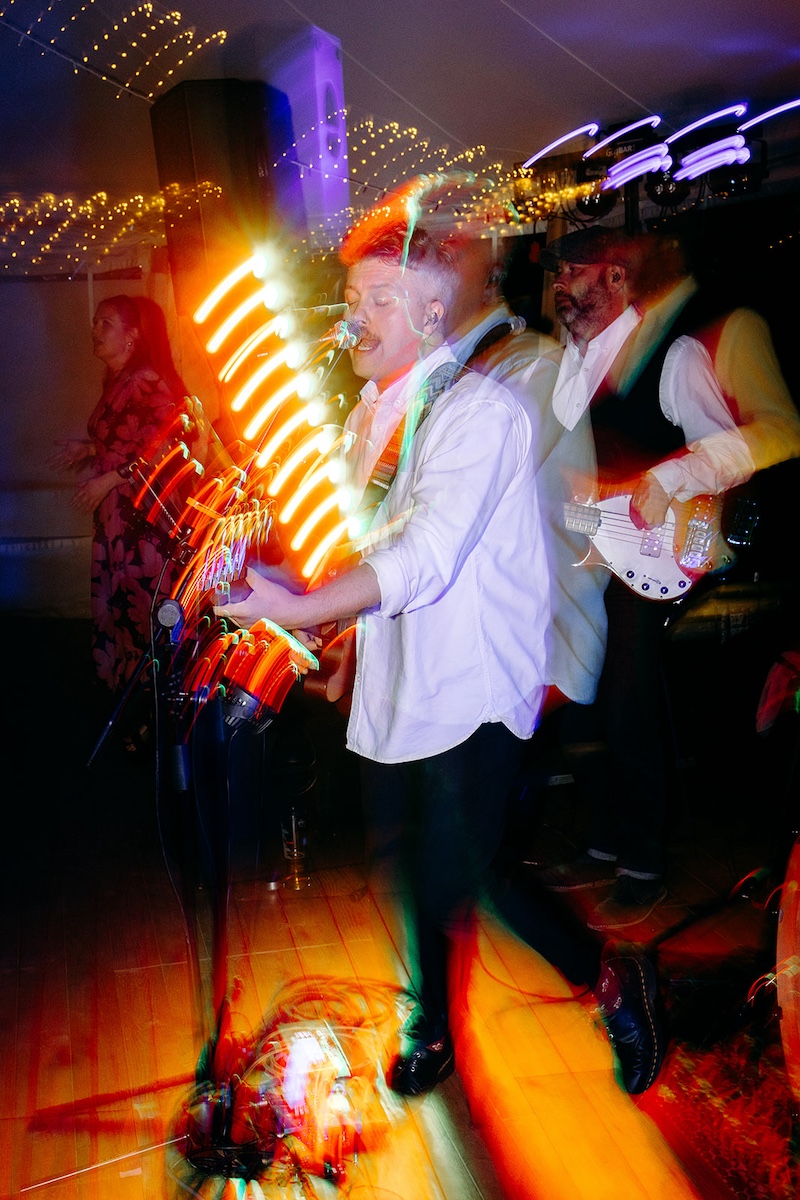 Energetic dance floor moment with guests cheering and confetti still on ground at Eyam Hall wedding.