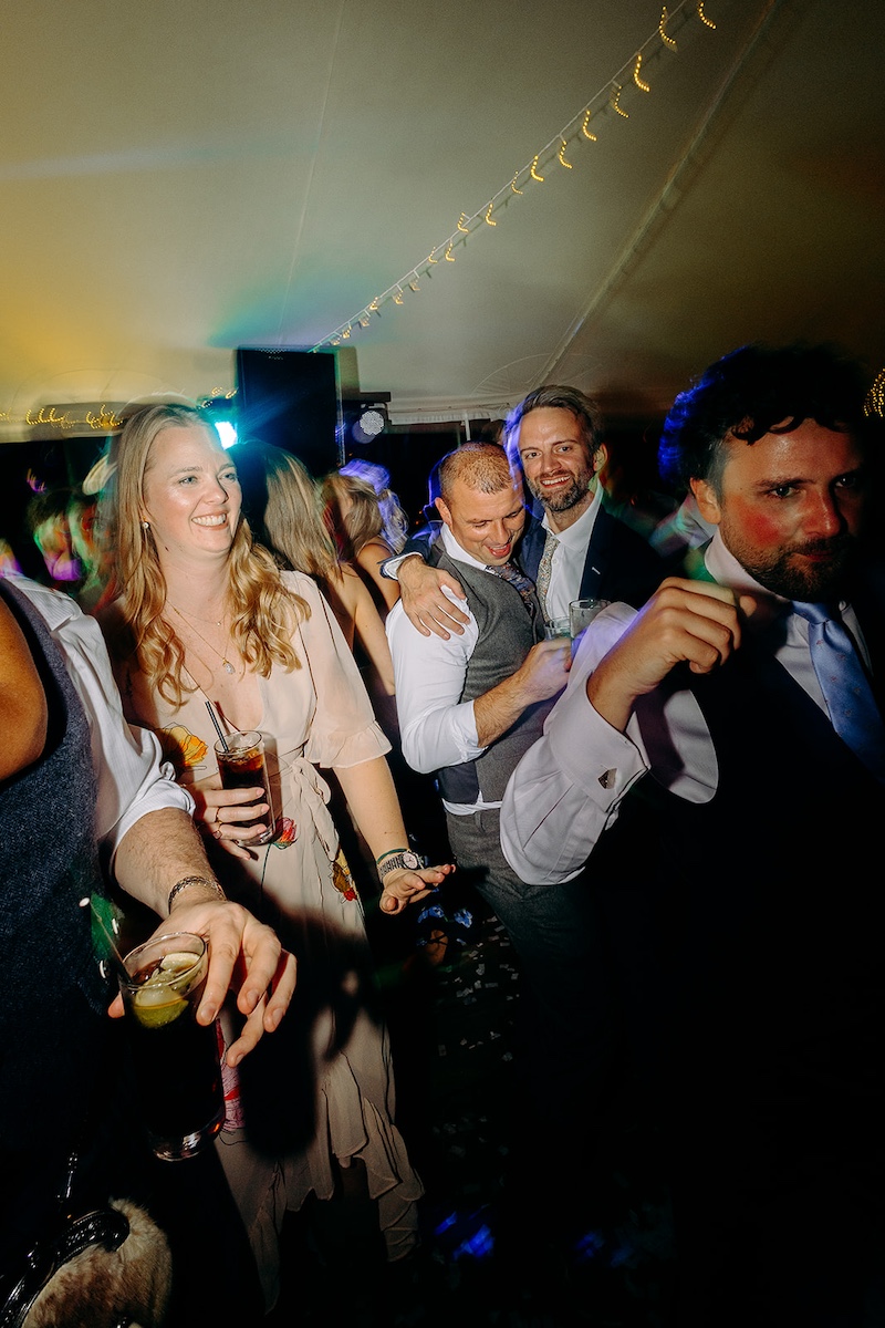 Energetic dance floor moment with guests cheering and confetti still on ground at Eyam Hall wedding.