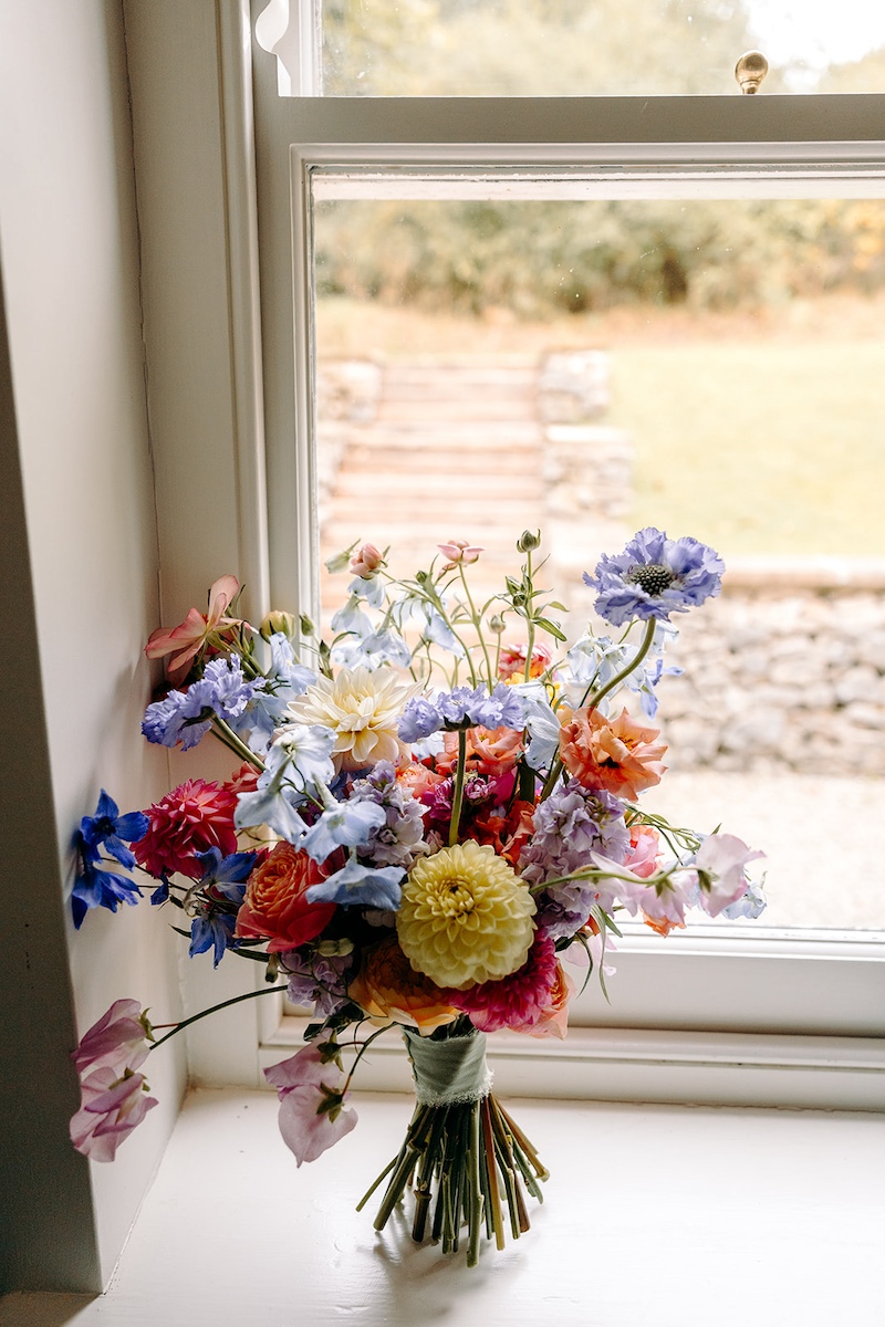 Close-up of colourful bouquet outside Eyam Hall church before ceremony.