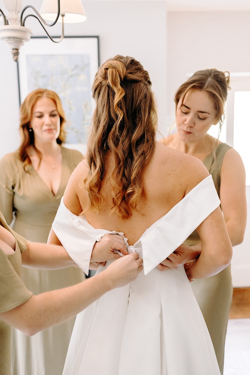 Bridesmaids helping bride into her wedding dress during bridal prep – Eyam Hall wedding photography.