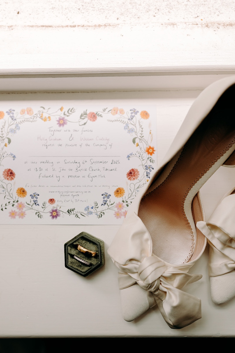 Flatlay of wedding invitations, rings and bridal details styled together before Eyam Hall wedding.