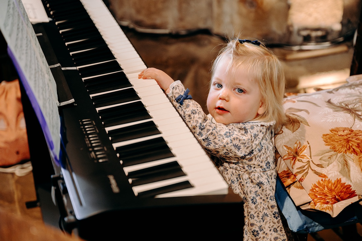 Natural photo of flower girl playing piano in Peak District church wedding.