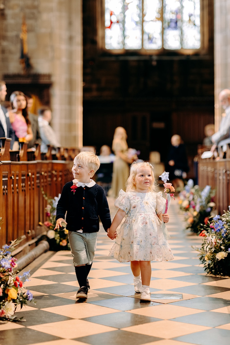 Natural photo of cute flower girl and page boy walking down the aisle of Peak District church wedding – Derbyshire wedding photographer.