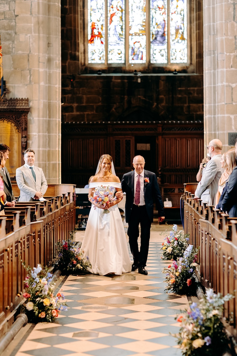 Bride and father of the bride walking down the aisle together for the ceremony at Eyam church.