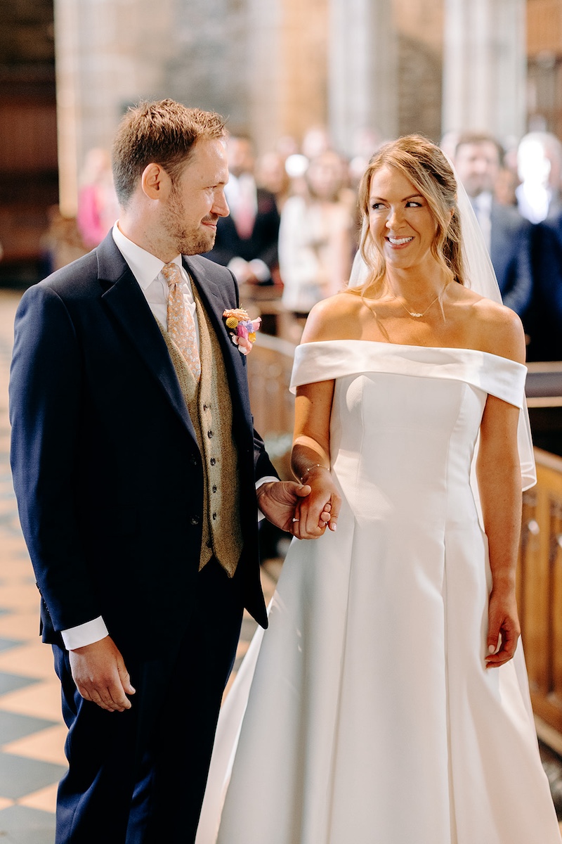 Bride and groom standing side by side at the front of Eyam church during their wedding ceremony – Derbyshire wedding photographer.