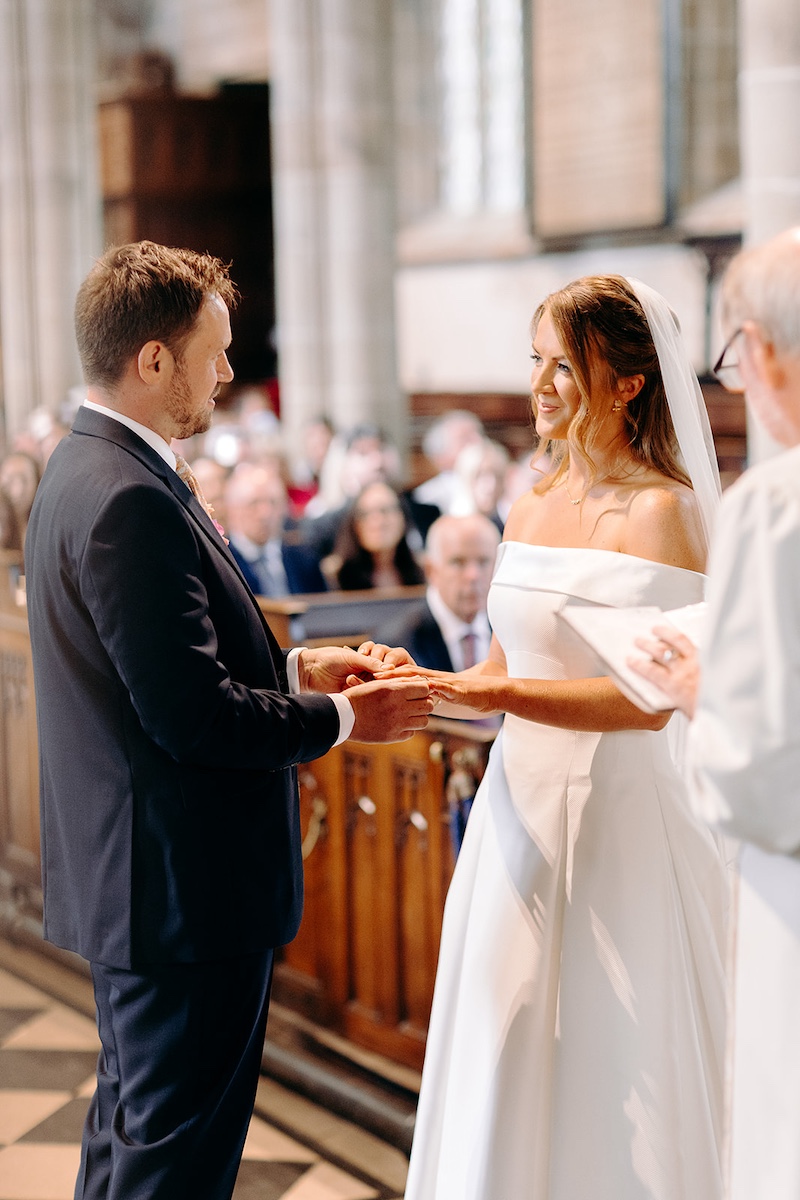 Bride placing ring on groom’s finger during Eyam Hall wedding ceremony – close-up moment.