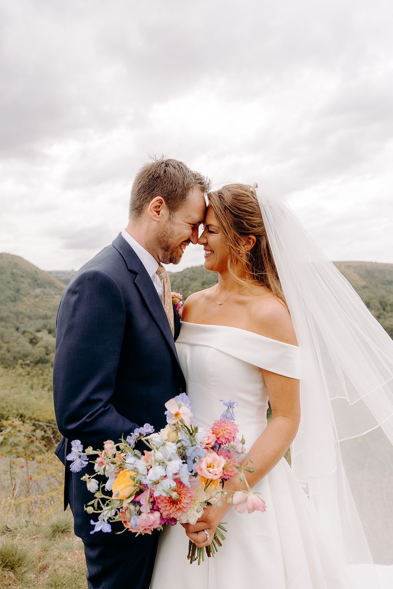Bride twirling playfully while groom smiles, Peak District hills behind – Derbyshire wedding photographer portraits.