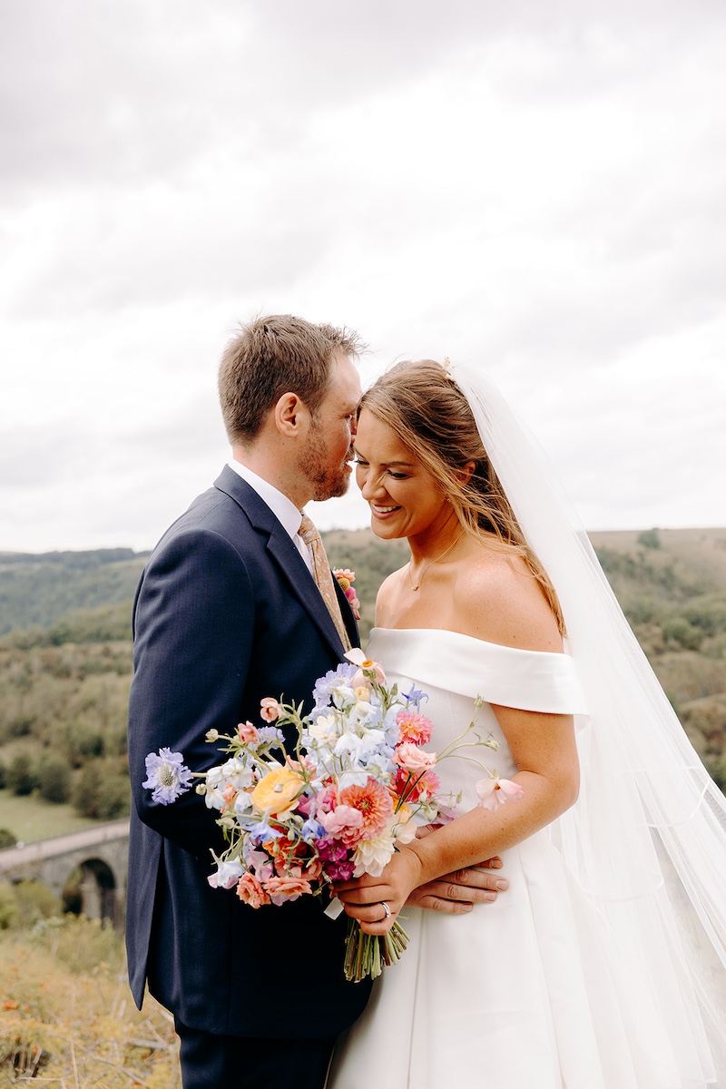 Bride and groom walking back toward road with dramatic Peak District views – Derbyshire wedding photography.