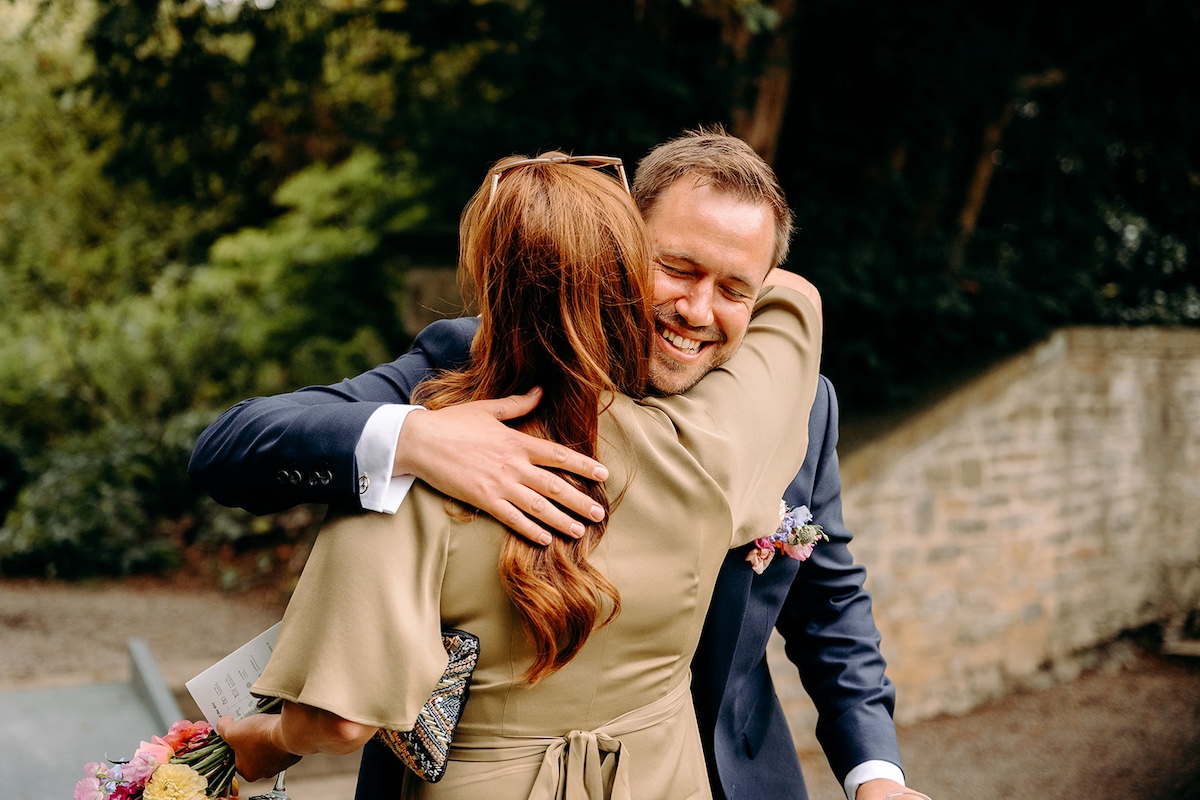 Candid photo of hugs and greetings during drinks reception at Eyam Hall marquee wedding.