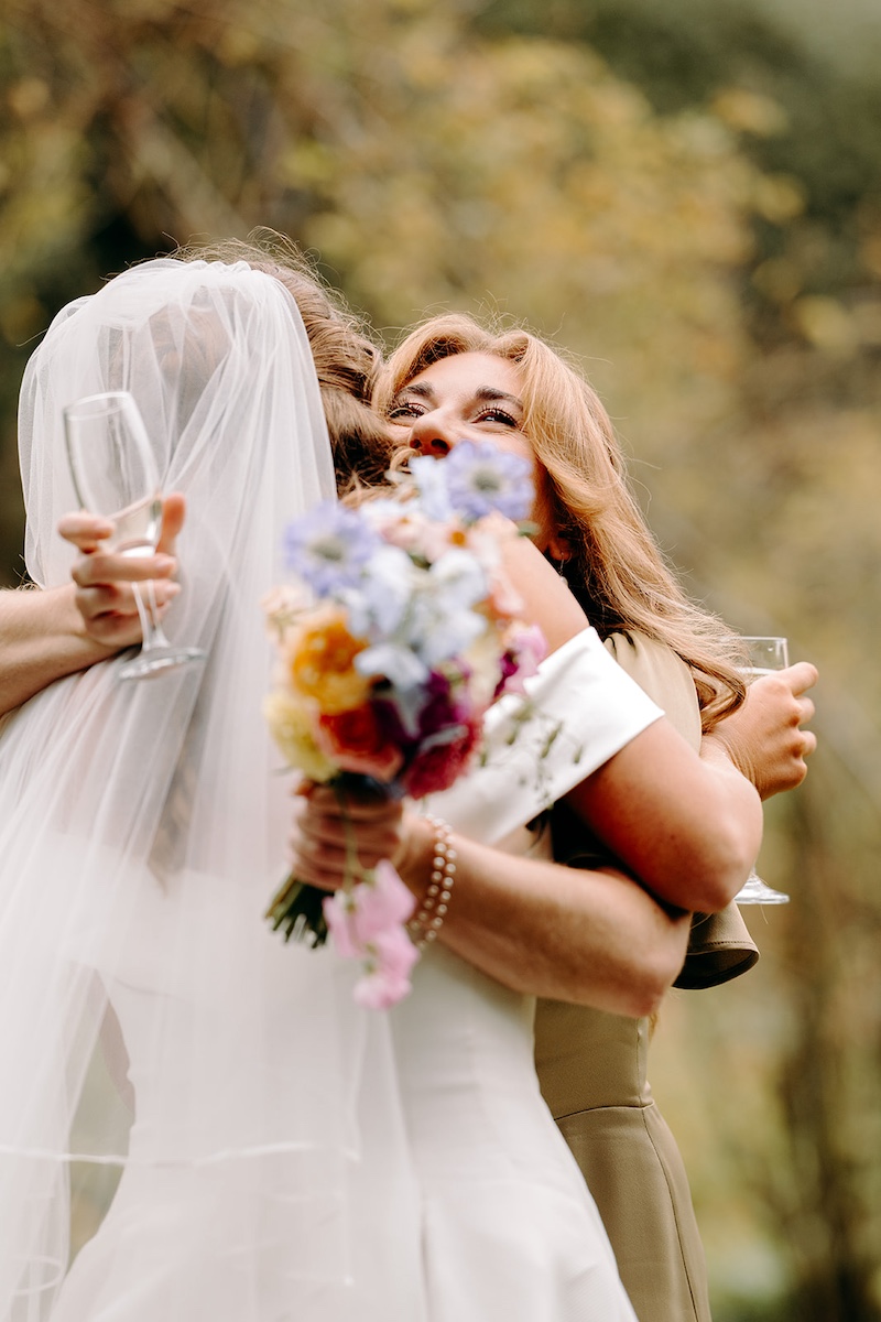 Candid photo of hugs and greetings during drinks reception at Eyam Hall marquee wedding.