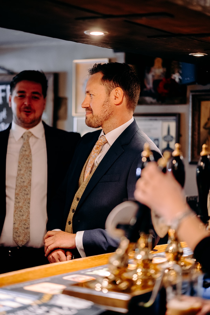 Candid groomsmne chatting and laughing outside in Eyam before the wedding ceremony.