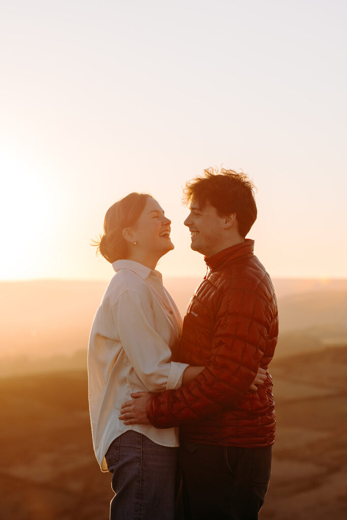 Joyful couple hugging during golden hour engagement shoot in the Peak District countryside