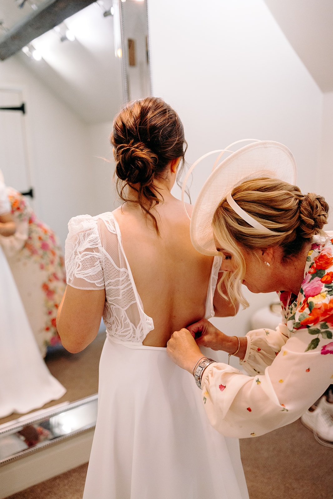 Bride's mum helping bride into wedding dress during emotional wedding preparations at Ashes Barns.