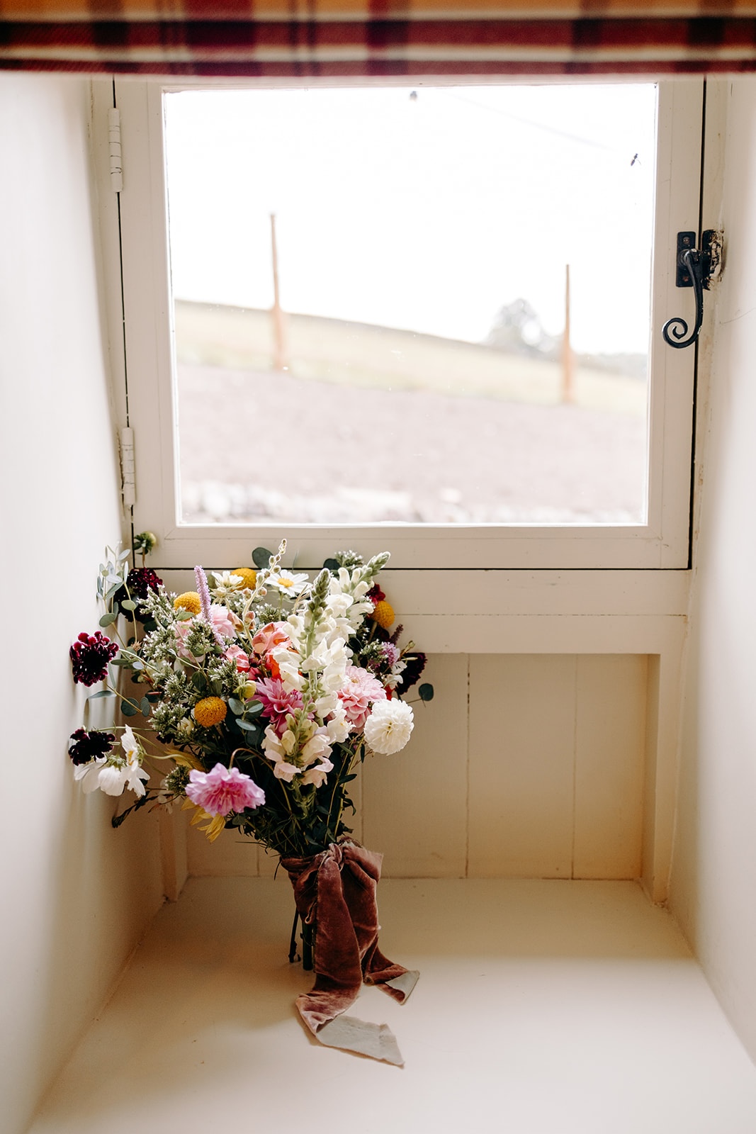 DIY bridal bouquet resting by a window with soft natural light at Ashes Barns.