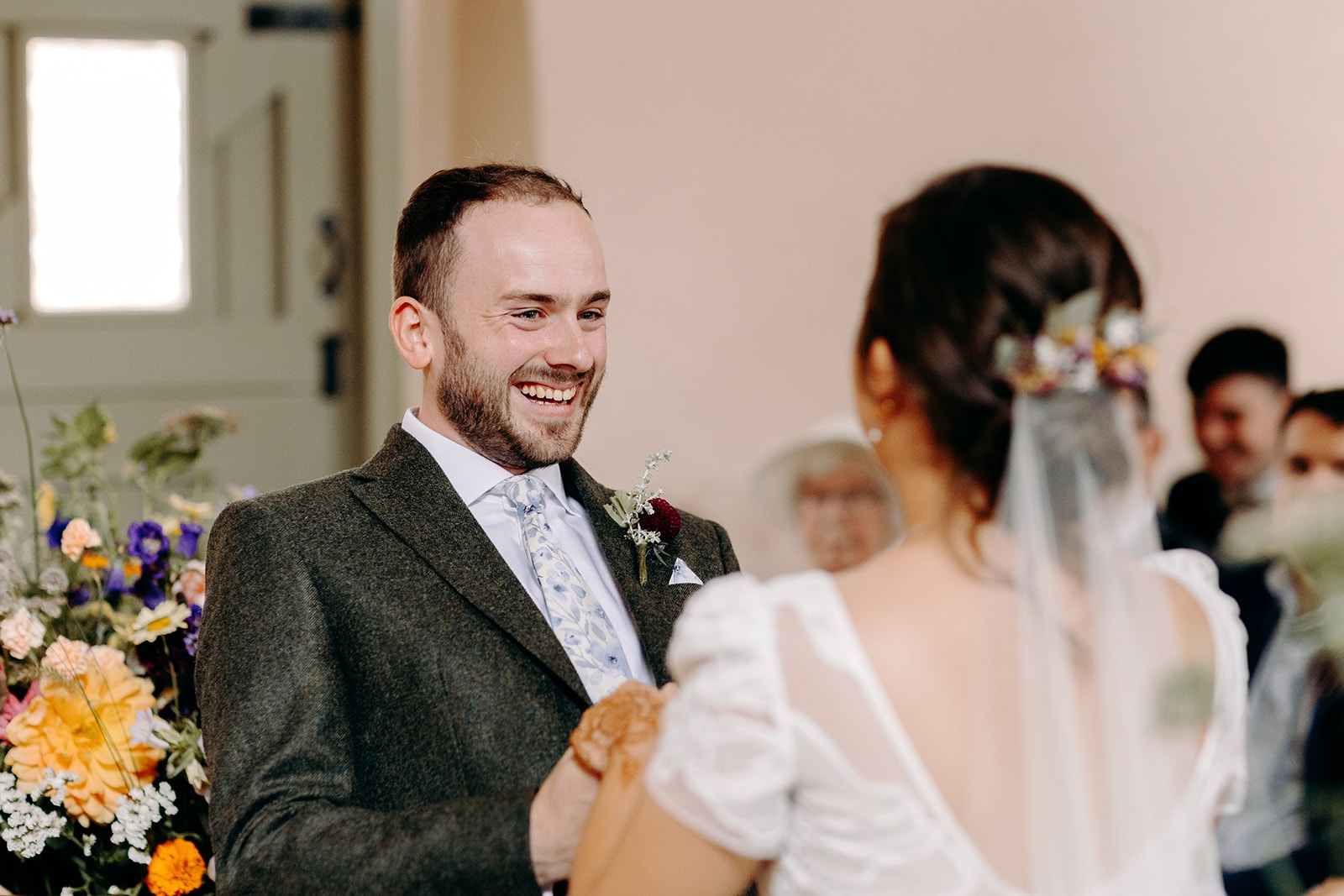 One partner smiling emotionally during vows at an intimate Ashes Barns wedding.