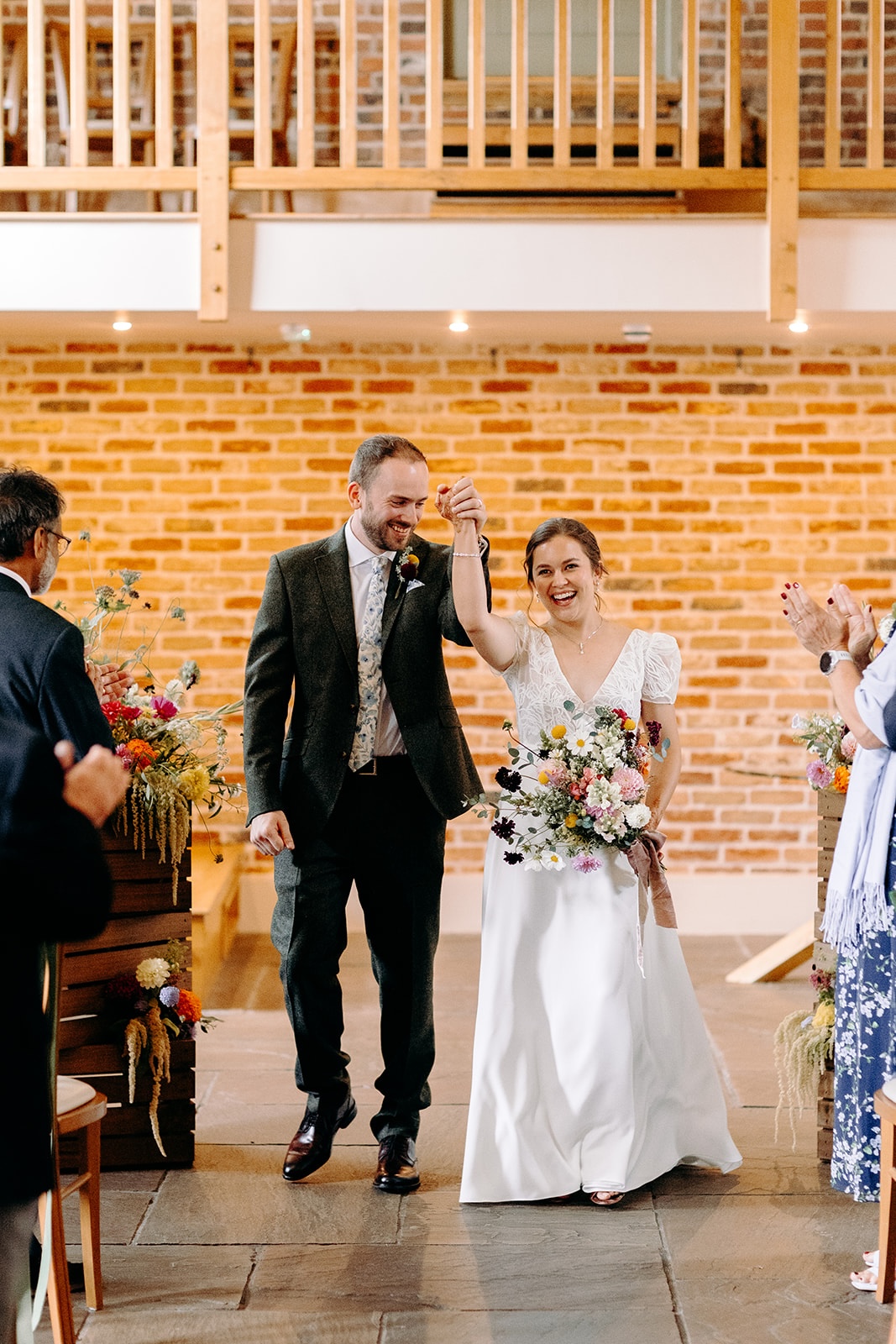 Couple walking back down the aisle smiling after getting married at Ashes Barns.