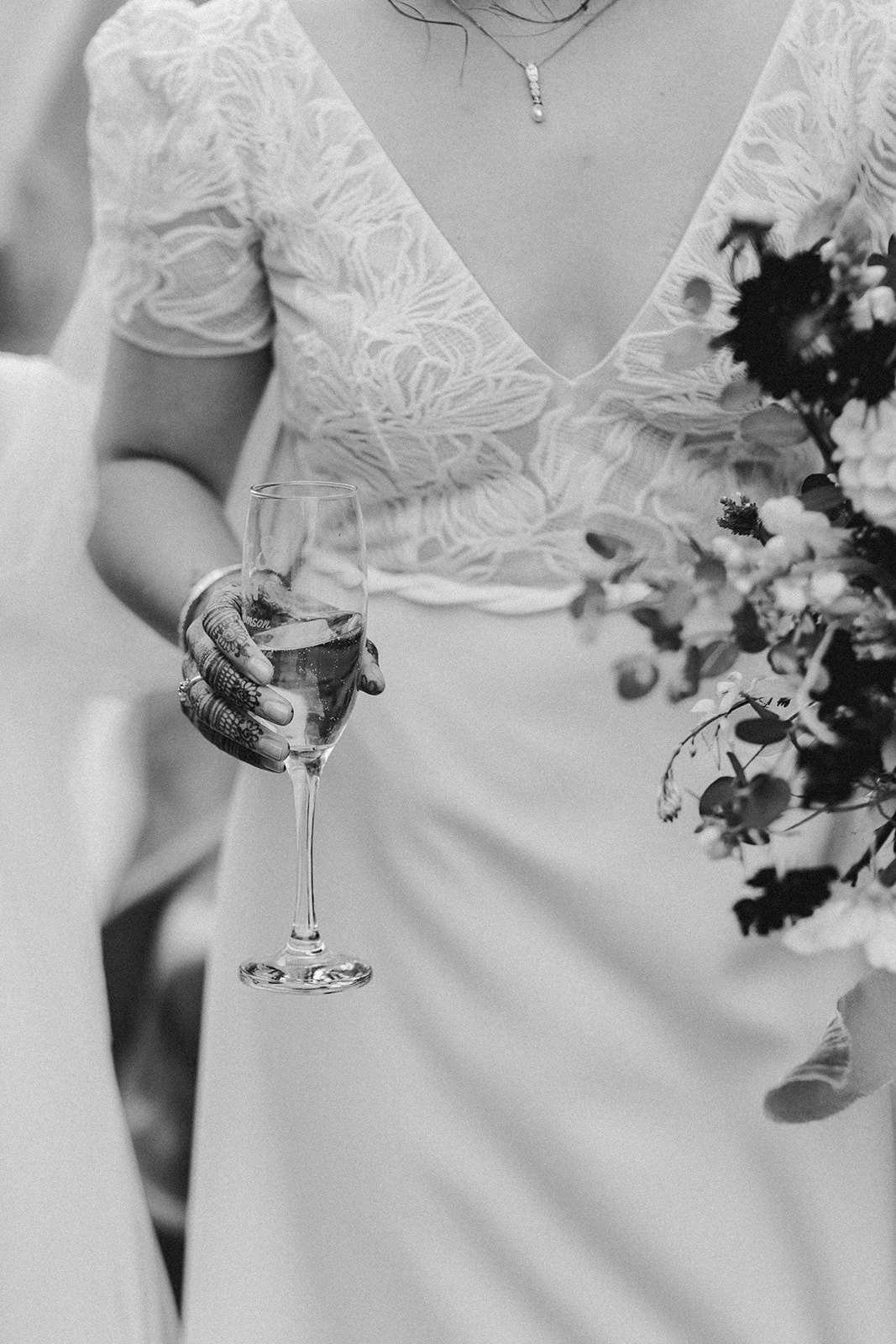Black and white close-up of the couple holding hands with wedding bouquet outside Ashes Barns.
