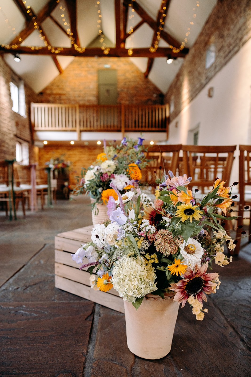 Floor-level floral arrangement in rustic pots inside Ashes Barns ceremony space.