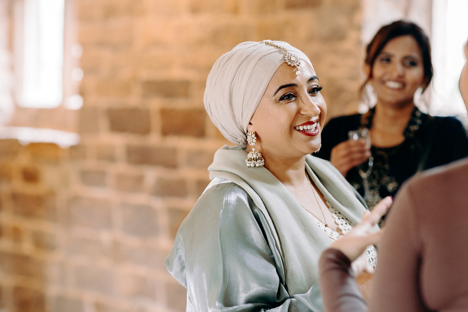 Smiling guest wearing a hijab chatting during drinks reception at Ashes Barns.