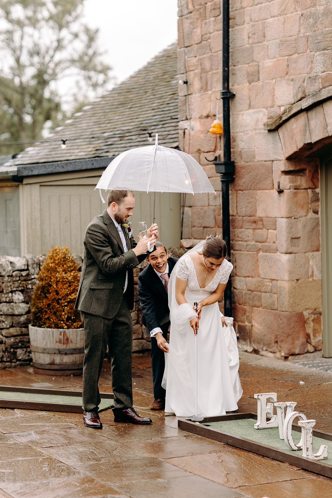 Couple sharing a moment under umbrellas outside Ashes Barns during the wedding day.