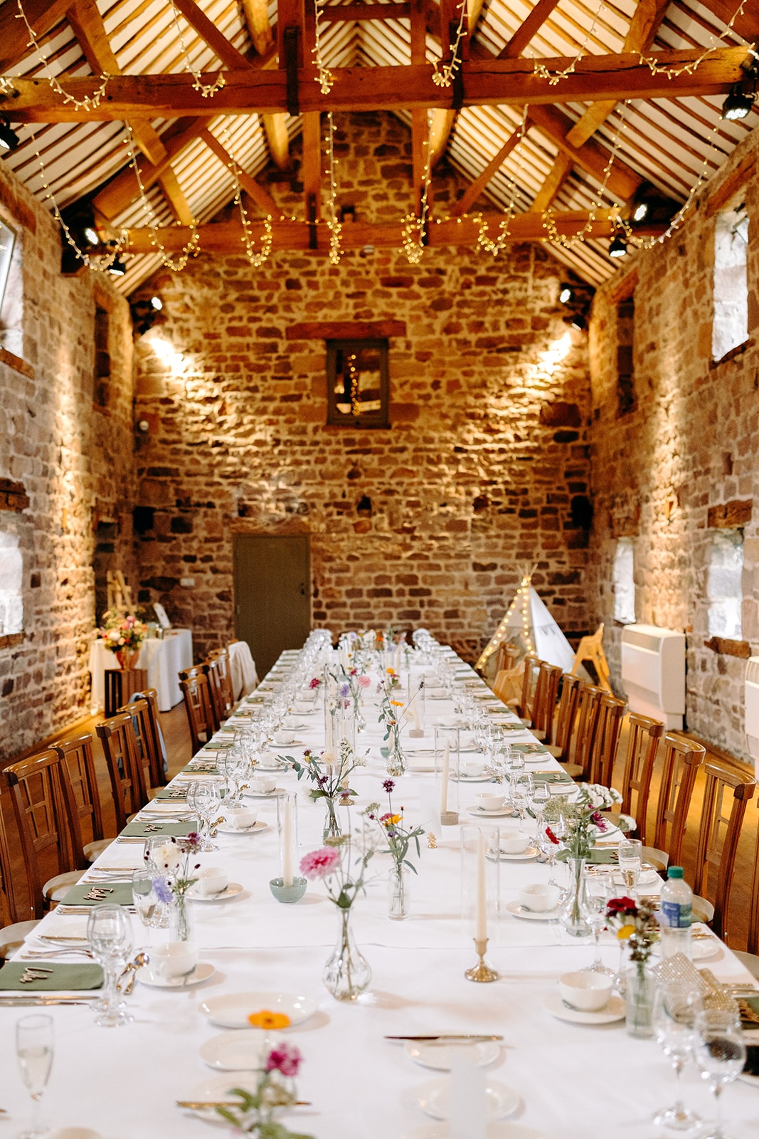 Long table laid out inside the stone barn ready for the wedding meal at Ashes Barns.