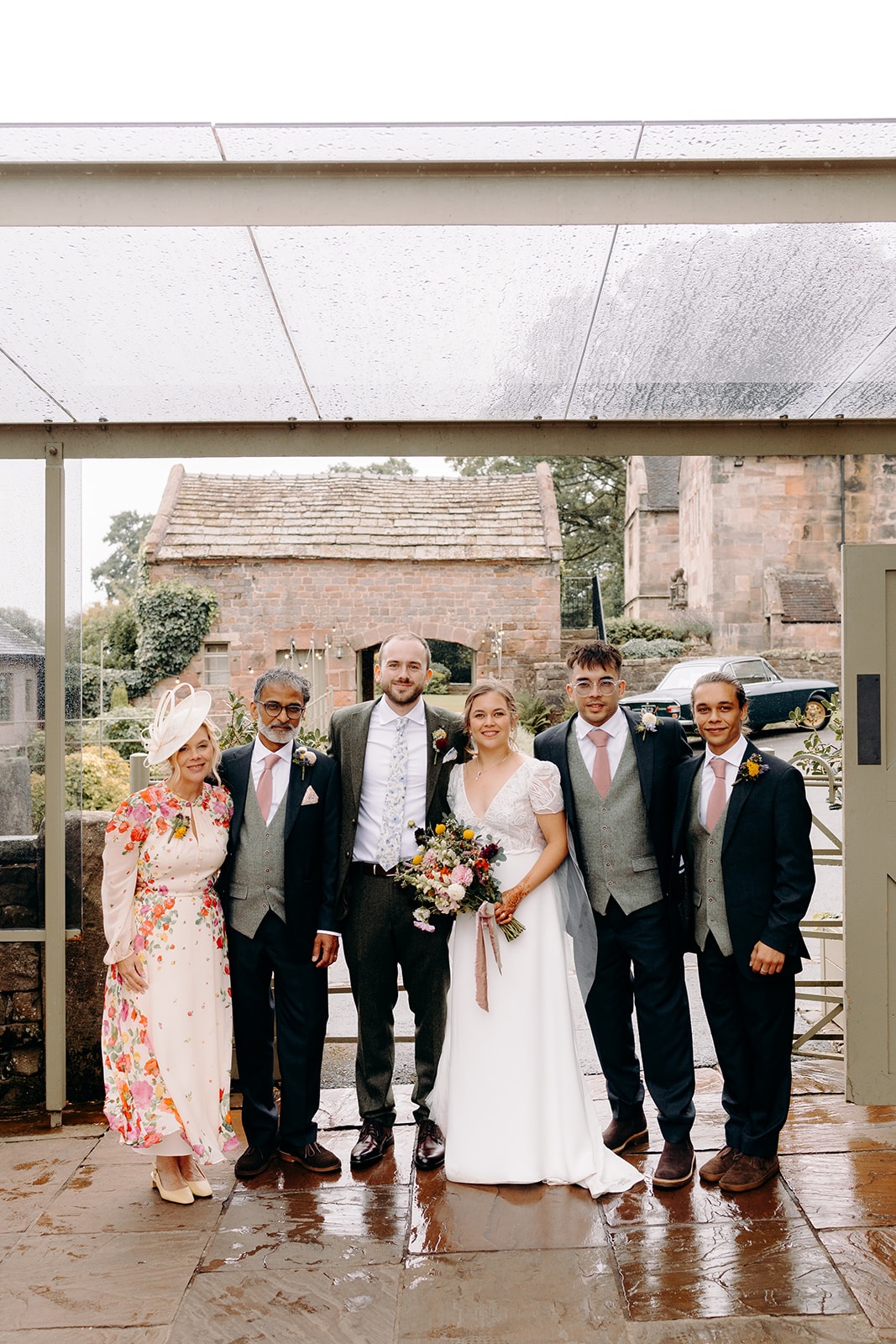 Group photo of wedding guests outside Ashes Barns despite the rain.