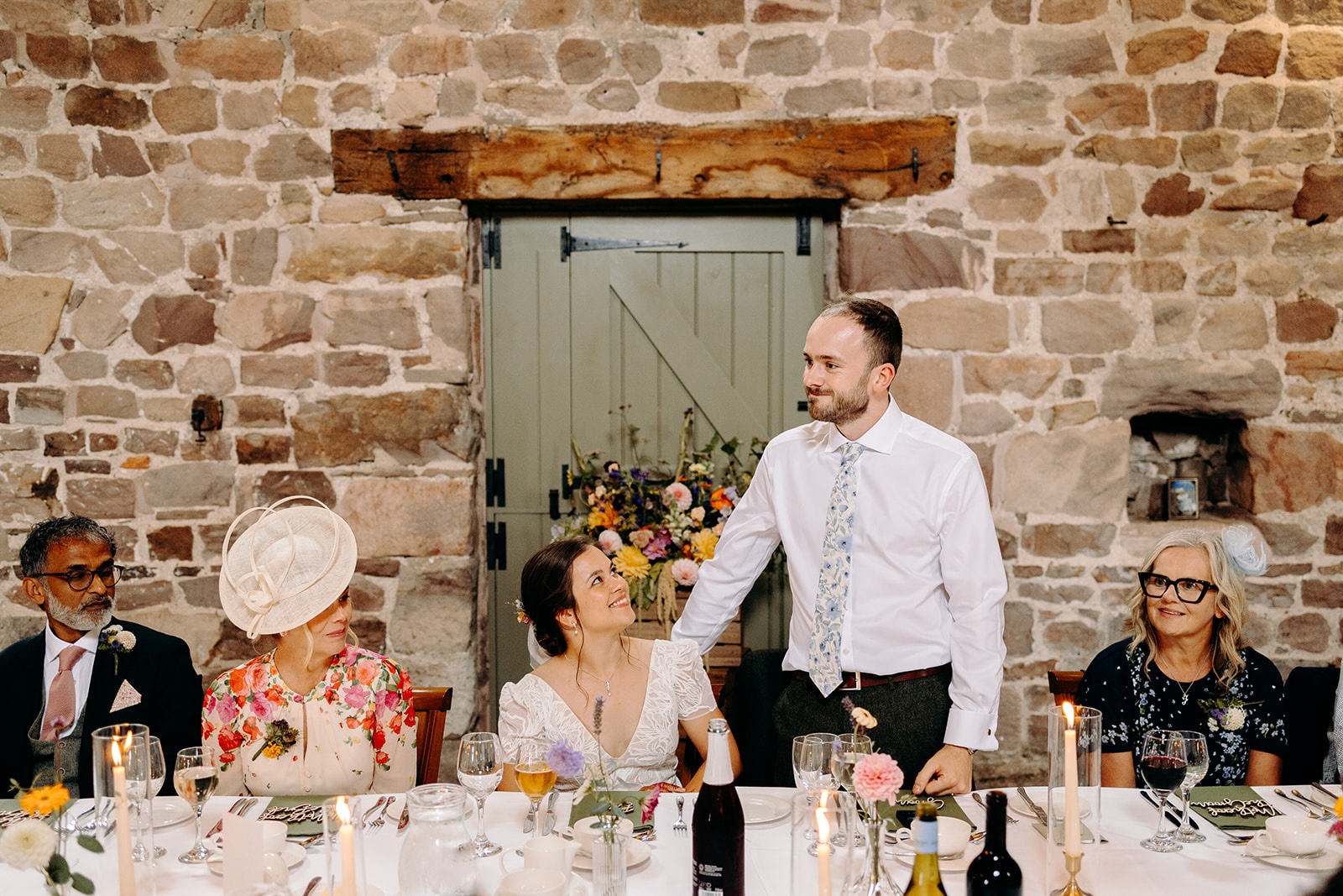 Groom standing to give a toast inside the rustic barn at Ashes Barns.