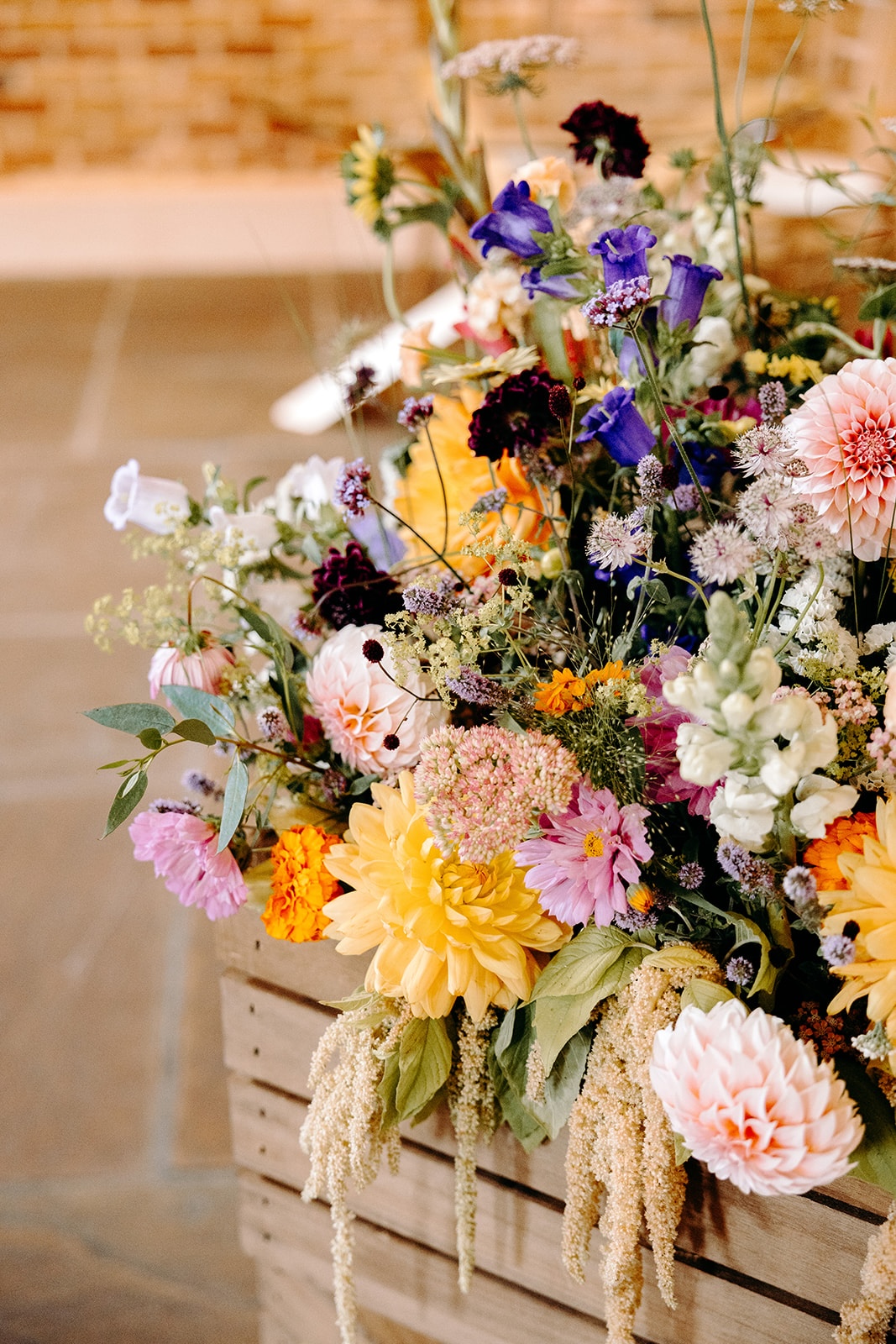 Bright, meadow-style wedding flowers arranged in wooden crates at Ashes Barns.
