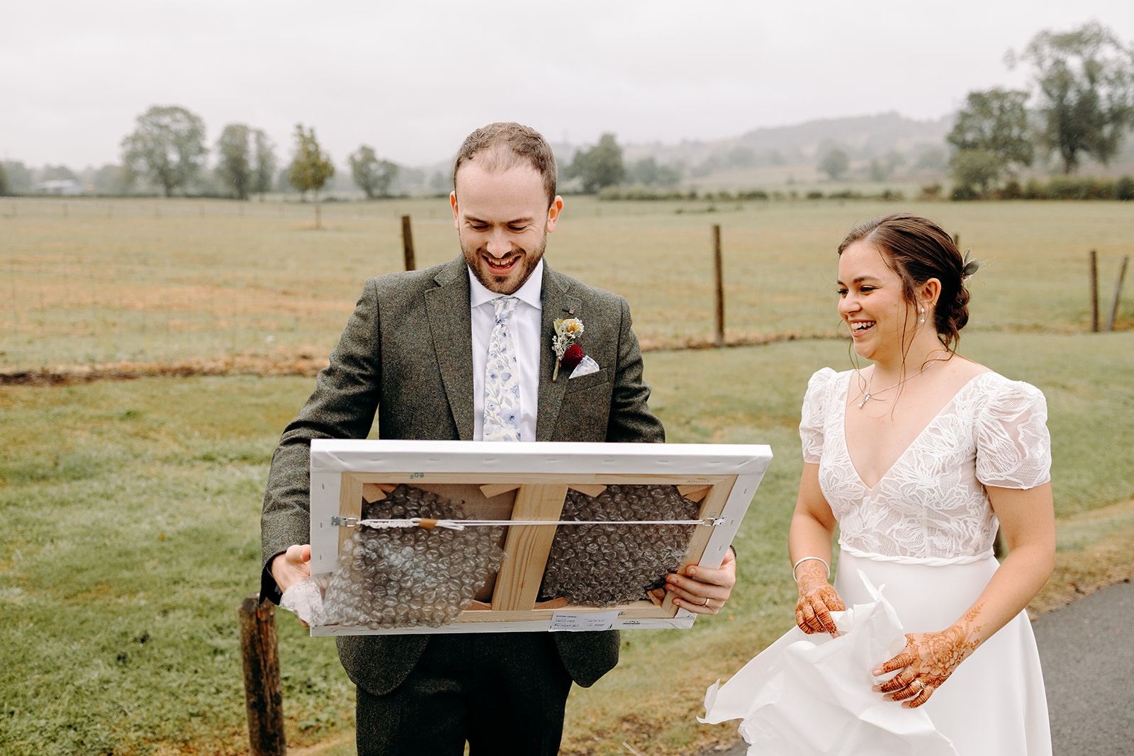 One partner holding a framed piece of artwork during relaxed wedding portraits near Ashes Barns.