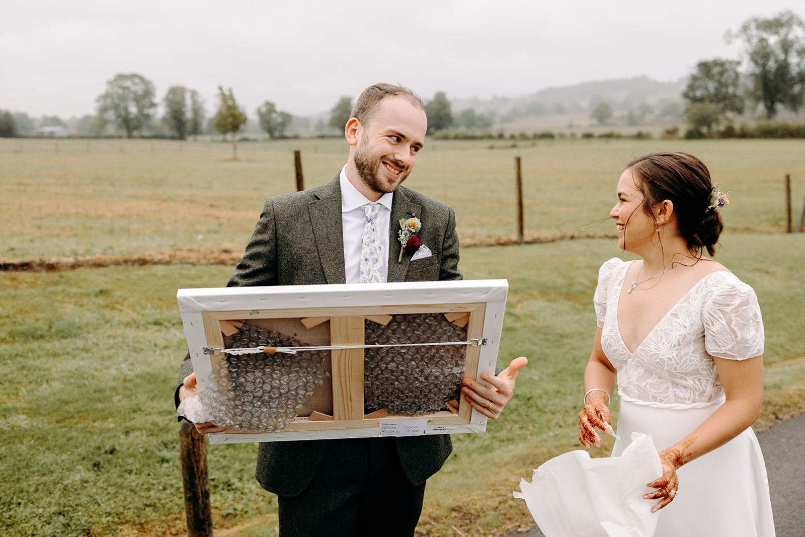 Couple laughing together while holding artwork during creative wedding portraits in the Peak District.
