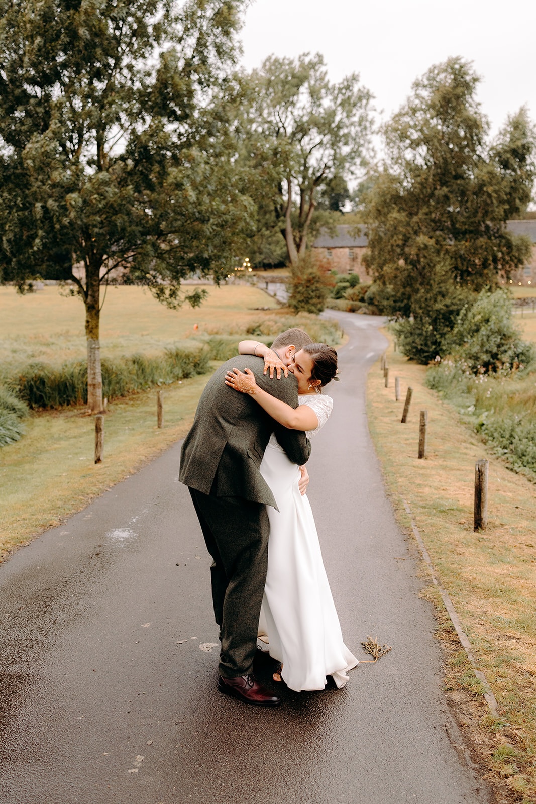 Couple sharing a hug on a rural lane during Ashes Barns wedding portraits.