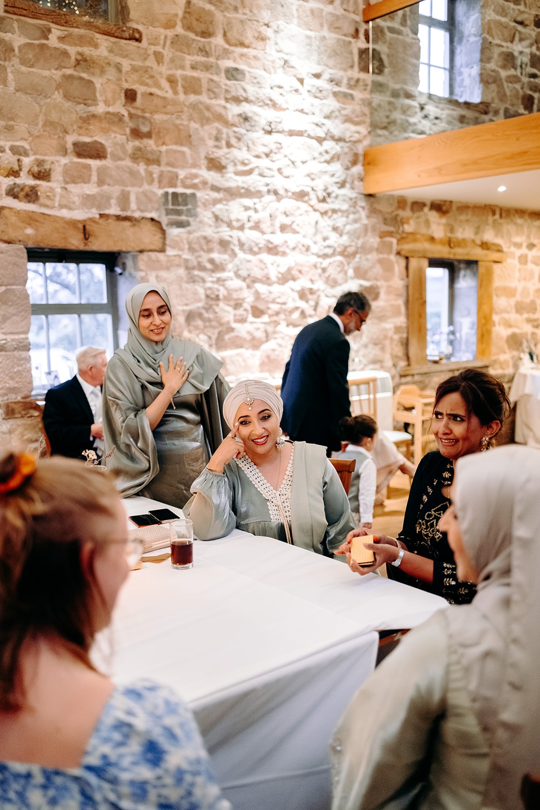 Friends chatting around candlelit tables as the evening reception continues at Ashes Barns.