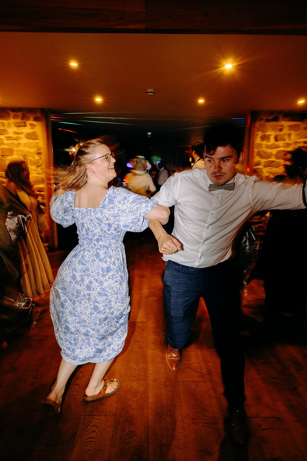 Couple spinning around on the dancefloor during a lively ceilidh dance at the Ashes Barns.