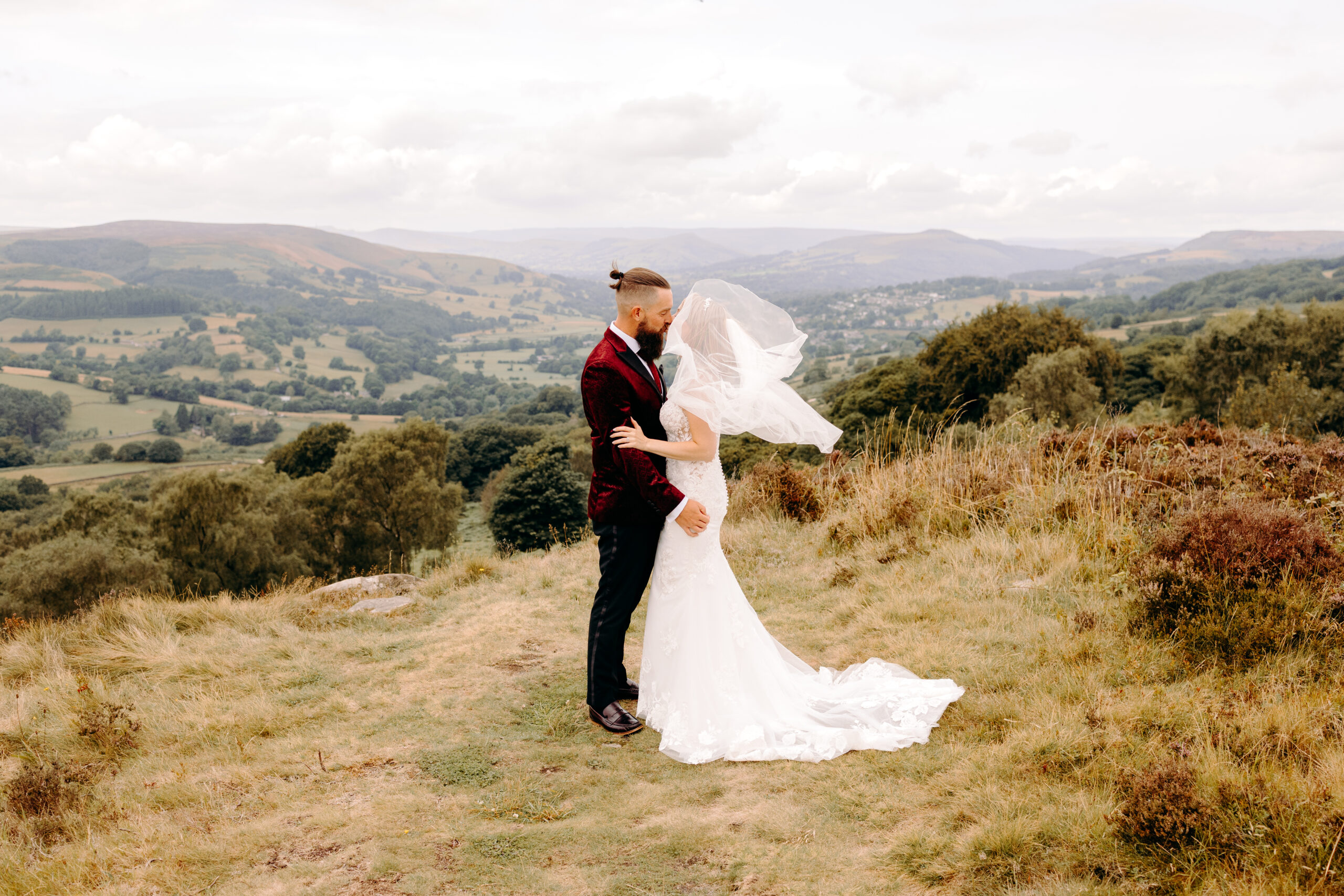 Couple hugging with sweeping Peak District backdrop after intimate wedding at Bakewell Town Hall.