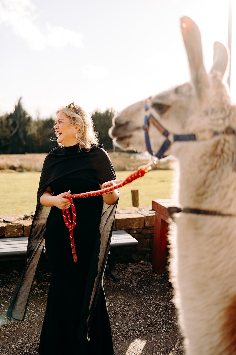 Wedding guest holding a llama lead during the drinks reception.