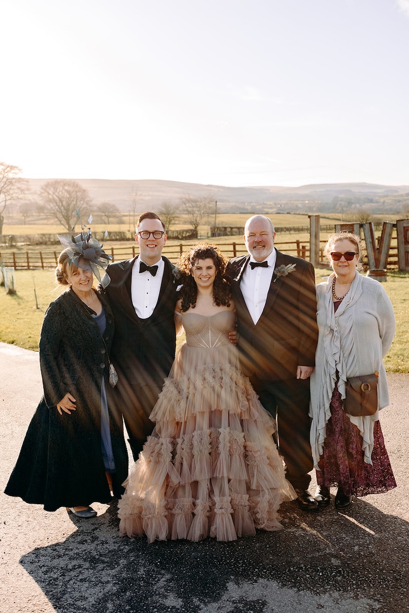 Bride and groom posing with family during group photos at The Wellbeing Farm wedding venue.