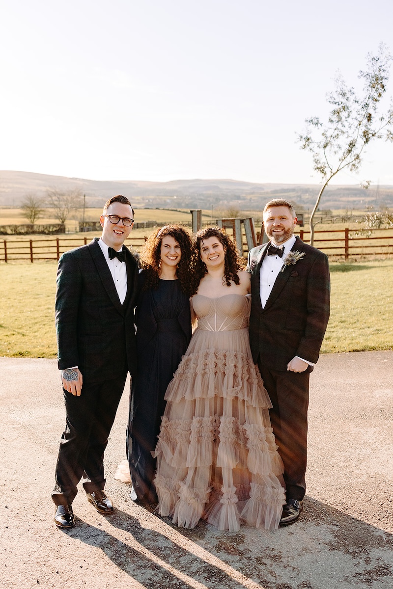 Bride and groom posing with friends during wedding party portraits outside the barn.