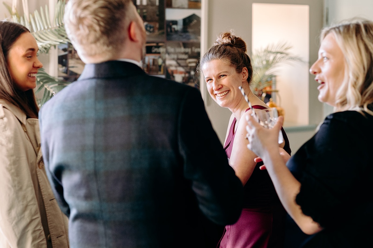Wedding guests talking together inside the rustic barn reception space.