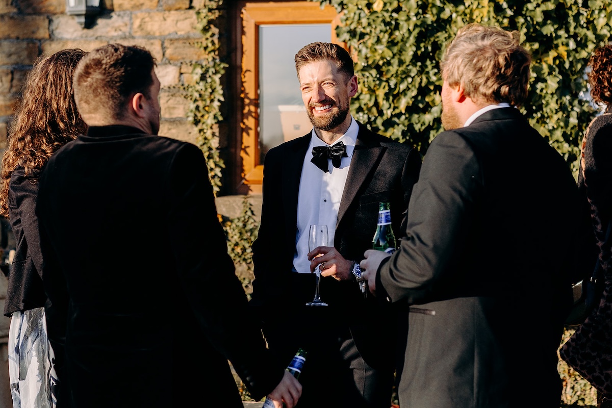 Groom chatting with friends in the courtyard during the evening celebration.