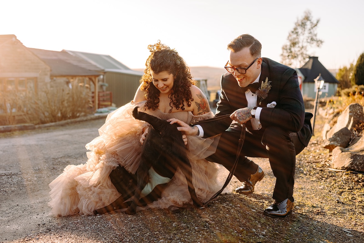 Groom playing with the dog during informal couple portraits photographed by a documentary wedding photographer.
