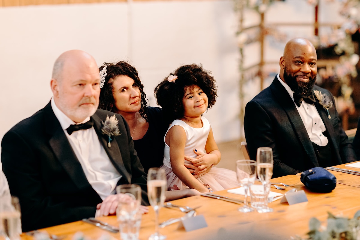 Friends sitting together and smiling during the reception meal photographed by a wedding photographer.